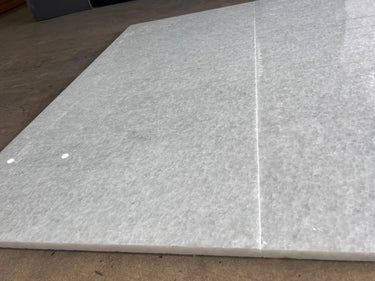 Polar white natural stone tile, 24x48 polished surface from RN, showing smooth, glossy finish with subtle veining and clean edges.