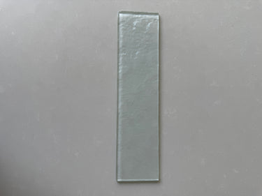 Close-up of Roca LUX Crystal 3x12 glass tile, showcasing its clear, reflective natural stone surface and sleek rectangular shape.