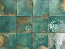 Mediterranean-inspired glazed porcelain backsplash in rich green tones
