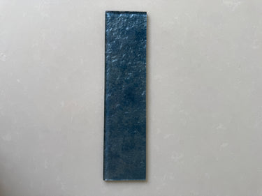 Roca Lux Indigo 3x12 glass tile, natural stone finish with blue and indigo hues, close-up of textured surface.