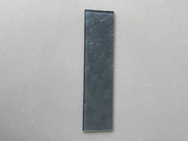 Close-up of Roca LUX Pewter 3x12 glass tile showing its natural stone texture and sleek, modern finish.