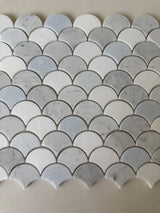 Natural stone tile featuring a blue mix, Carrara and Thassos marble, arranged in a fan pattern for backsplash or wall use by Roca.